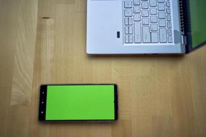 laptop and phone with green screen on single workplace table, chroma key, photo