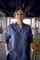 an  attractive middle age woman walks in a modern coworking neutral design, wearing wide leg pants and a silk blouse photo