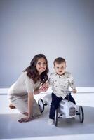 emotional mother playing with her little son and his toy car photo