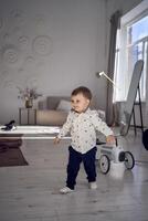 a smiling toddler walks across the room to his mother photo