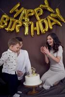 emocional padres reloj como su hijo golpes fuera el velas en el cumpleaños pastel foto