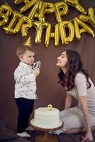 muy emocional mamá y su pequeño cumpleaños chico comiendo pastel foto