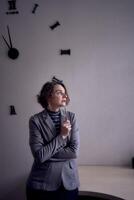 woman standing in office in front of clock photo