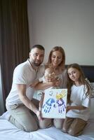 family holds a painting with their hand prints photo