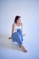 young teenage girl sits on a white cyclorama in the studio photo