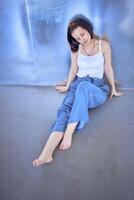 young teenage girl fighting brain cancer at photo shoot in studio sitting on floor, leaning against metal wall, reflection