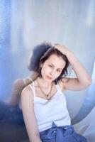 young teenage girl fighting brain cancer at photo shoot in studio sitting on floor, leaning against metal wall, reflection