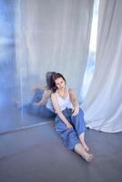 young teenage girl fighting brain cancer at photo shoot in studio sitting on floor, leaning against metal wall, reflection