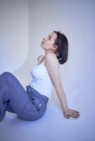 young teenage girl sits on a white cyclorama in the studio photo