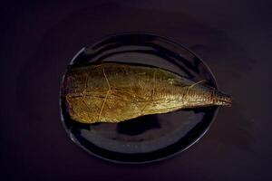 appetizing hot smoked golden horse mackerel on a black background photo