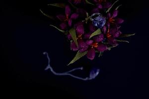 amethyst ring and a pendant of paper flowers in a blue vase on a black background photo