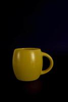 grande amarillo taza en un negro antecedentes foto
