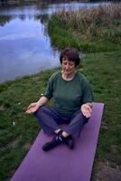 un antiguo mujer meditando en el Mañana en el banco de el río, llegó desde hogar por bicicleta foto