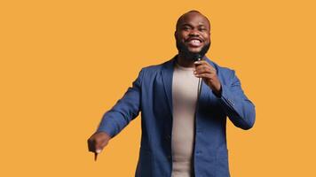 African american motivational speaker holding monologue using microphone, gesturing with hands, studio background. Energetic BIPOC speaker talking during presentation using mic, doing speech, camera B video