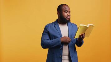 African american orator reading book aloud, narrating story for audience. BIPOC person presenting literature novel, reciting from pages, entertaining spectators, studio background, camera B video