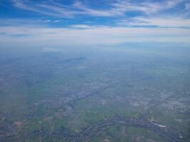 Aerial view of lands, sky and clouds seen through airplane window photo