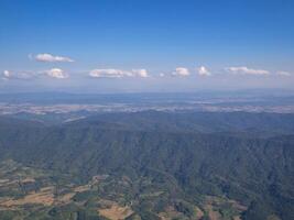 Aerial view of mountains, sky and clouds seen through airplane window photo