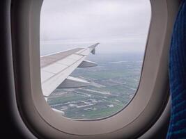 Aerial view of lands and clouds seen through airplane window photo