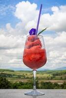 Fresh healthy watermelon smoothie in the glass against the background of sky, clouds, and mountains. Healthy nutrition and vitamins photo