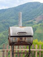 de cerca de antiguo barbacoa parrilla estufa con montañas antecedentes foto