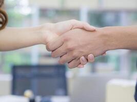 Business handshake after contract meeting in office. Young Woman and man shaking hands after meeting or negotiation to join partner business. Success joins partnership working with teamwork photo