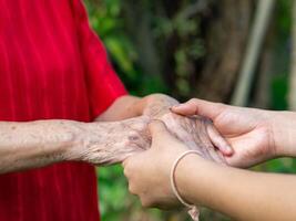 Close-up of hands a granddaughter's holding hands a grandmother's. Concept of aged people and healthcare photo