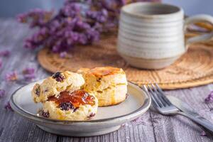 Side view of traditional British scones on a plate with a teacup and flower blurred background. Space for text photo