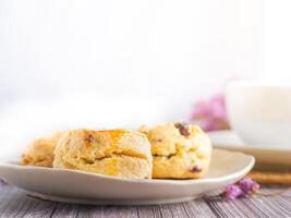 de cerca de tradicional británico bollos en un plato y un té caliente taza con borroso antecedentes. espacio para texto foto