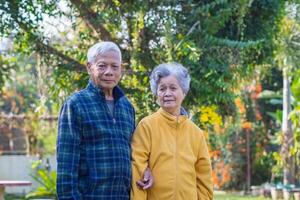 Senior couple looking at the camera while standing in a garden. Concept of aged people and healthcare photo