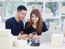 An Asian young couple is working while sitting in the office. Concept of business and e-commerce photo