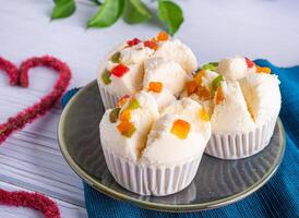 Side view of Thai steamed cupcakes topped with dry fruit on a plate on a blue cloth placed on a wooden background. Khanom pui fai in Thai. Traditional Thai food style photo