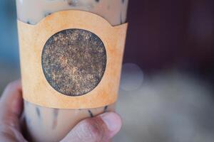 Close-up of an iced coffee cup in a woman's hand in the cafe shop. Space for text photo