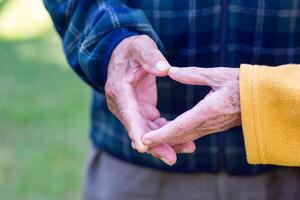 Close-up of the elderly couple showing making a heart with fingers. Concept of aged people and love photo