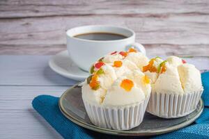 Side view of Thai steamed cupcakes topped with dry fruit on a plate on a blue cloth with a white coffee cup background. Khanom pui fai in Thai photo