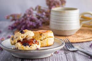 Close-up of traditional British scones on a plate with a tea cup and flower blurred background. Space for text photo