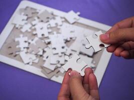 Hands of a woman holding and connecting jigsaw puzzle with a blue background and sunlight effect. Space for text. Concept of business and partner photo