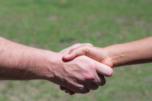 Close-up shot of man shake hands with a woman while standing in a garden. Concept of teamwork and partnership photo