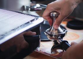 Close-up of hands barista presses ground coffee using a tamper. The process of making coffee step by step photo