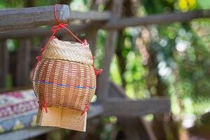 Sticky rice basket container from bamboo hanging on wooden with nature background. Space for text photo