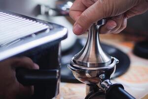 Close-up of hands barista presses ground coffee using a tamper. The process of making coffee step by step. Concept of beverages photo