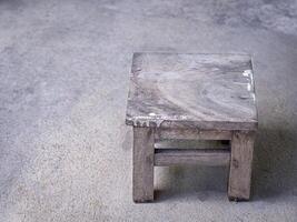 Close-up of vintage wooden stool on a concrete floor. Space for text photo