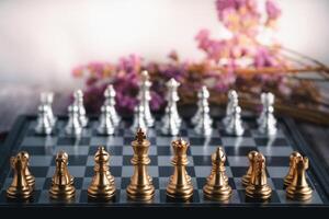 Front view of a chess game on a chessboard with purple flowers blur background. Business game competitive strategy. Concept of strategy for business photo