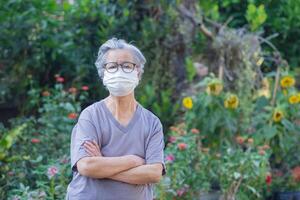 Senior woman with short gray hair, wearing glasses and wearing a face mask for protecting covid-19, coronavirus, bacteria, pollen grains, air pollution PM 2.5, and more. Healthcare concept photo