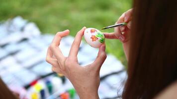ragazze' mani dipingere Pasqua uova con vernici di diverso colori nel il Aperto aria. acquerello pittura su uova. avvicinamento di mani video