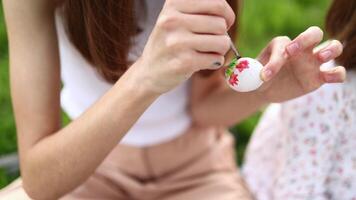 Girls' hands paint Easter eggs with paints of different colors in the open air. Watercolor painting on eggs. Close-up of hands video