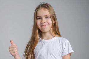 caucásico niña en blanco camisa da pulgares arriba para calidad. foto