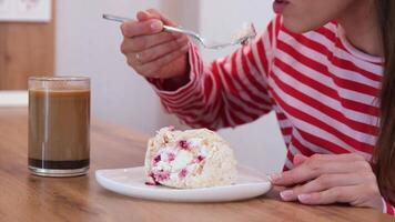 donna mangiare meringa rotolo torta con crema e lamponi seduta nel il cucina o cenare camera video