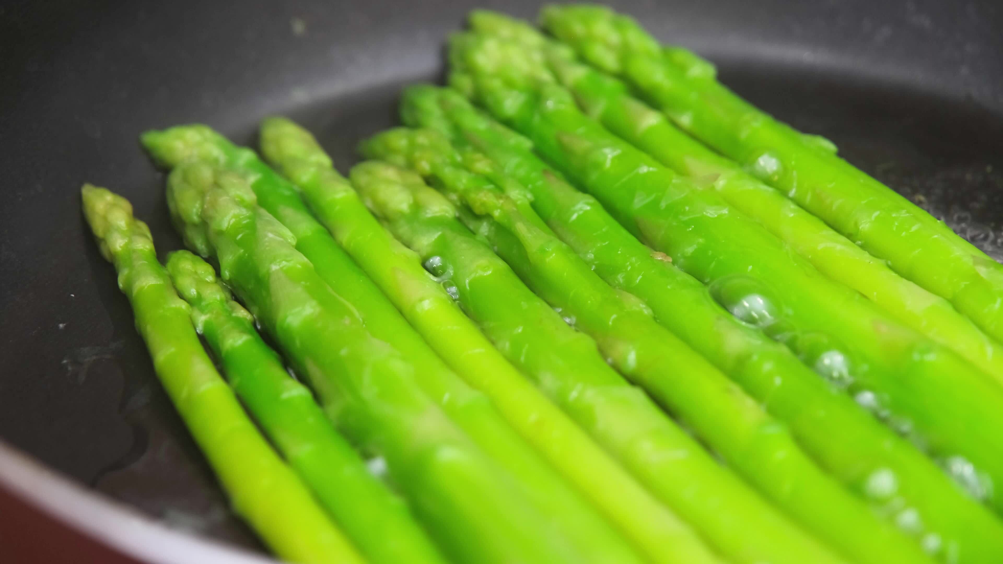 Healthy food woman cooking fresh asparagus in a pan in the kitchen