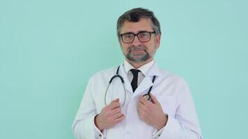 Portrait of a senior doctor in white suit with stethoscope on blue background video