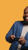 Vertical Upset man showing thumbs down sign gesturing holding controller, disapproving of games. Displeased BIPOC person against gaming, doing rejection hand gesture, studio background, camera A video